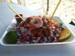 Ceviche with fish and seafood - prawns, squiand octopus. Served with half lime, red salsa, onions and tomatoes.