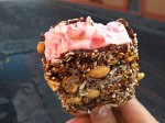Strawberry ice creams in chocolate with dried fruits, nuts, shredded coconut and with a big strawberry at the bottom. 