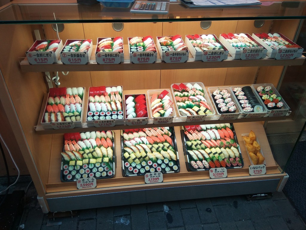 A fake, colorful sushi in front of a restaurant, encourages you to step in and have a great meal.