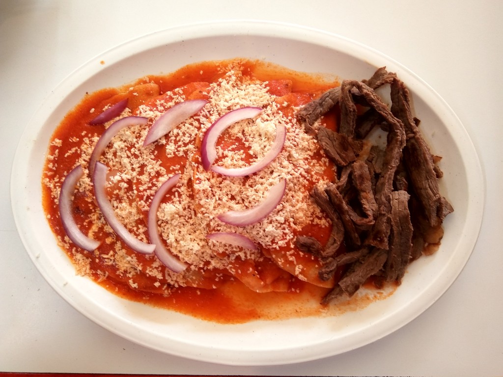 Enchiladas with beef and salsa roja - spicy red salsa, topped with cheese and onion slices.