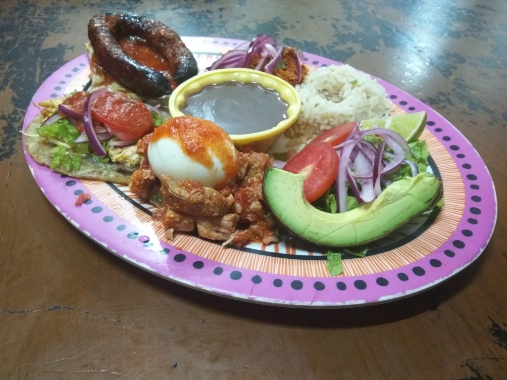 Plato winik with cochinita, lomitos, poc-chuc, longaniza asada, panuchos; served with a boiled egg, avocado, salad and frijoles.