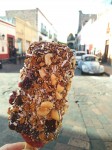 Strawberry ice creams in chocolate with dried fruits, nuts, shredded coconut and with a big strawberry at the bottom. 