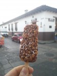 Coconut ice creams in chocolate with cereals and coconut flakes.