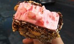 Strawberry ice creams in chocolate with dried fruits, nuts, shredded coconut and with a big strawberry at the bottom. 