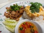 Omelet on rice with fried pork and garlic served with chilis in a fish sauce